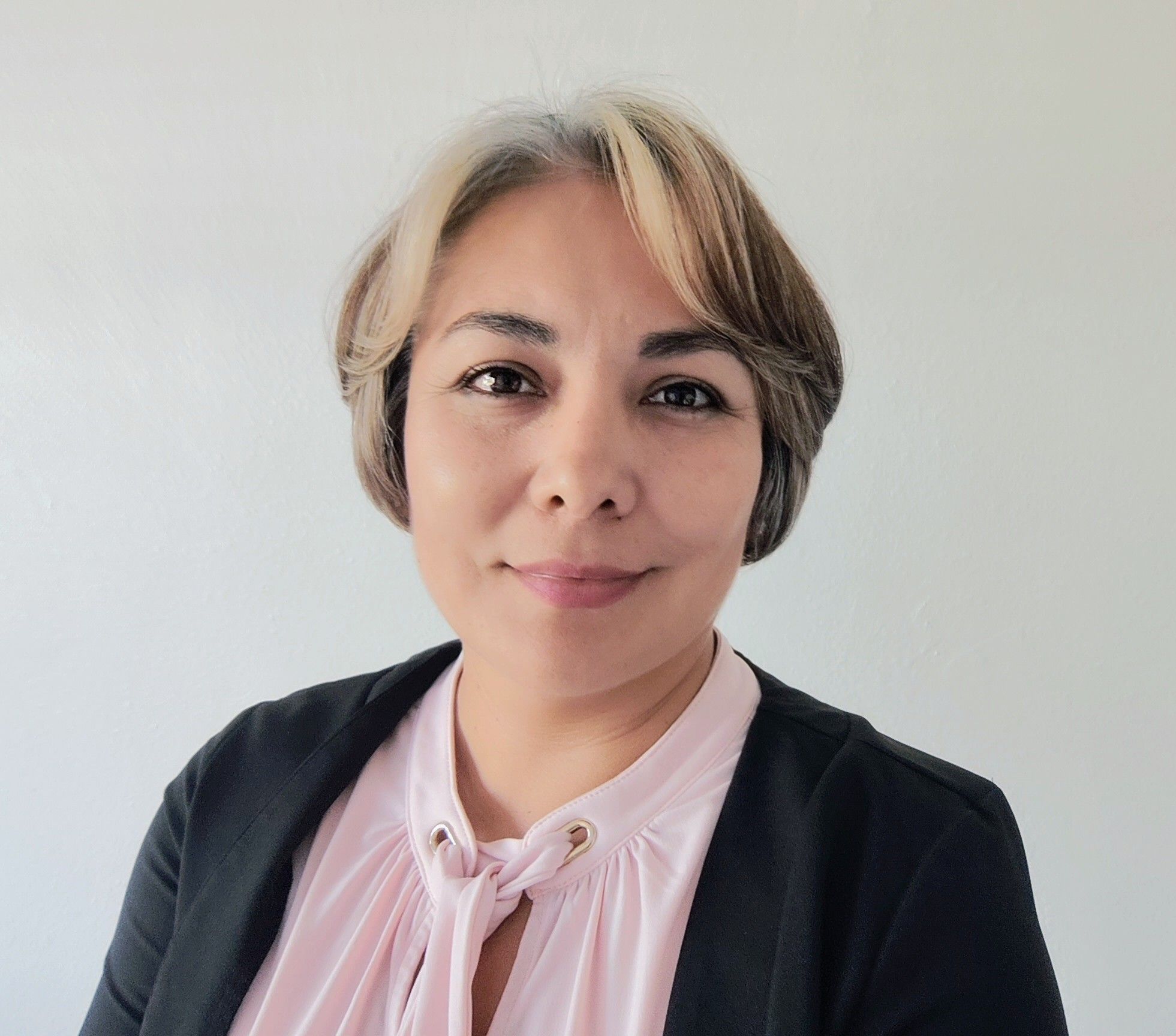 Woman with medium length blonde hair in pink shirt with black jacket