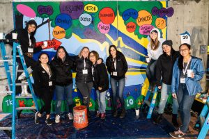 Group of volunteers in front of a mural.